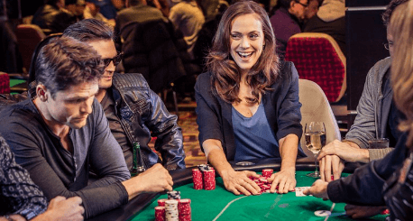 Table game and the people surrounding the table are having a great time shown by the smiles on their faces.